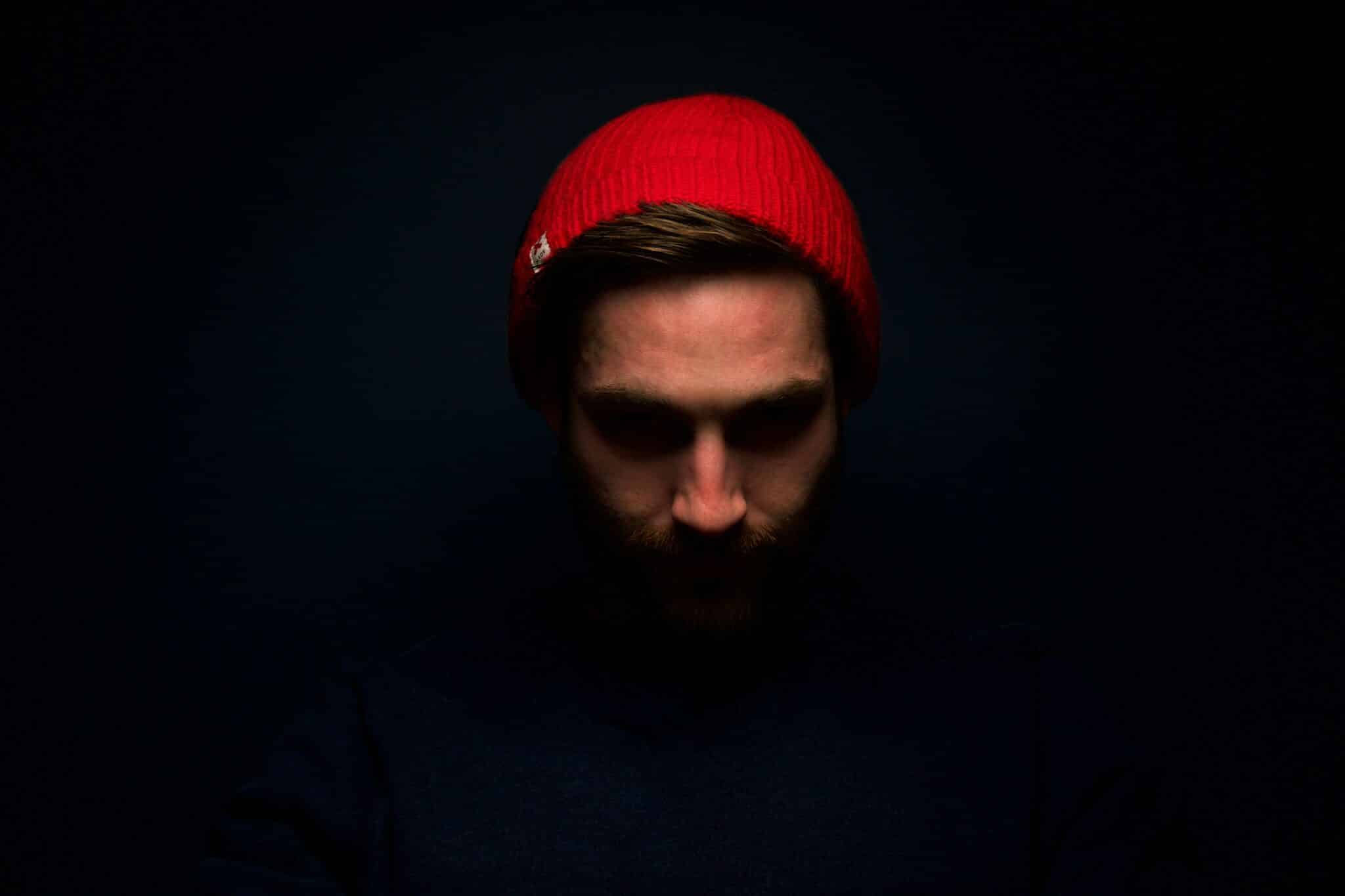 Man Wearing Red Knit Cap in Dark Room